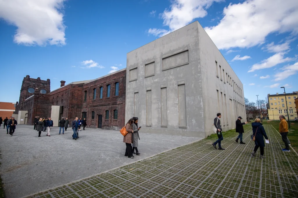 Galerie Plato Ostrava – spojení industriální minulosti a současné architektury Budova galerie Plato v Ostravě propojuje původní industriální architekturu historických jatek s moderní minimalistickou přístavbou, před níž se pohybují návštěvníci.