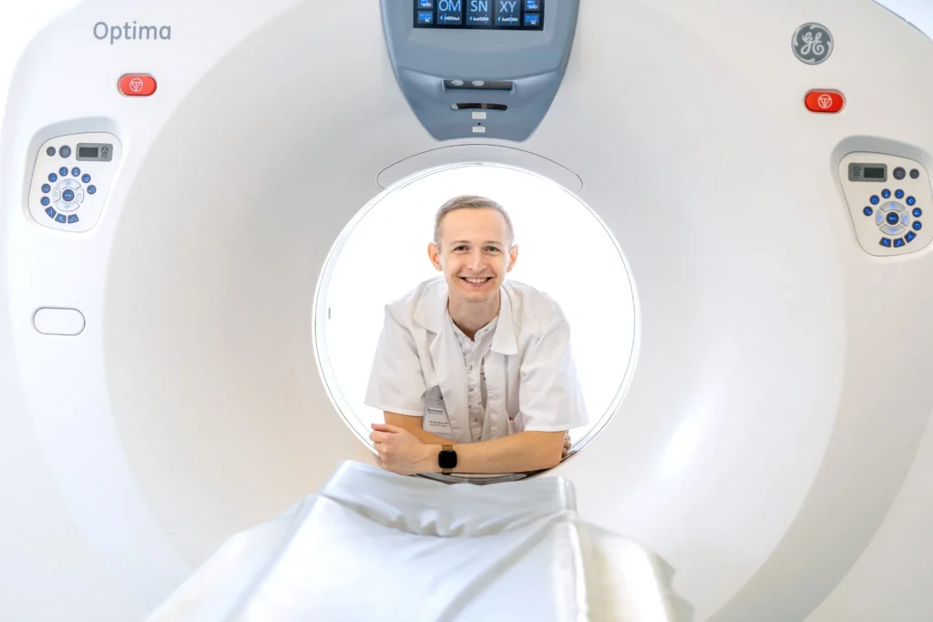 Radiolog v bílém plášti je u CT přístroje v radiologickém pracovišti; Penta Hospitals v Nemocnici Roudnice nad Labem testuje využití umělé inteligence v radiologii.
