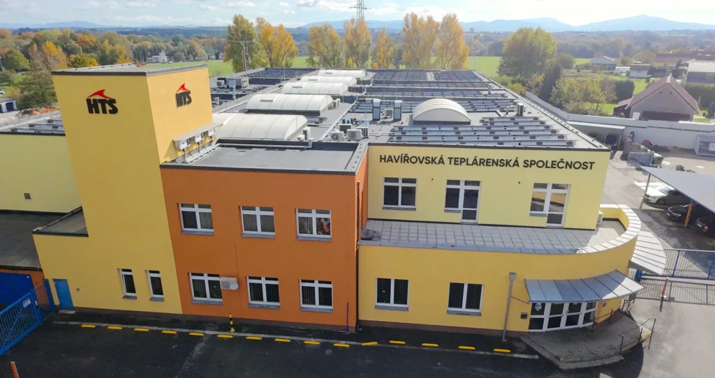 Aerial view of the Havířov Heat Supply Company (HTS) building with rooftop solar panels and the company name on the facade.