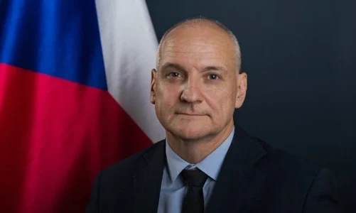 Václav Bartuška, velvyslanec České republiky ve Spojeném království, na oficiálním portrétu před českou vlajkou.