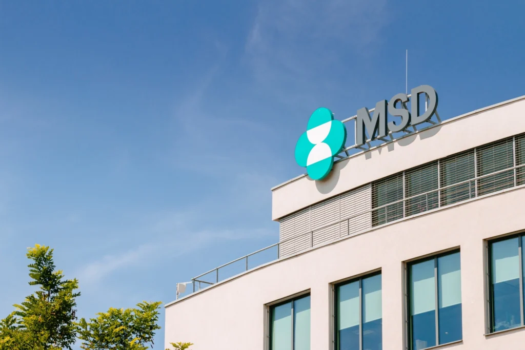The upper part of the MSD headquarters in Prague with the company logo on the roof against a blue sky.