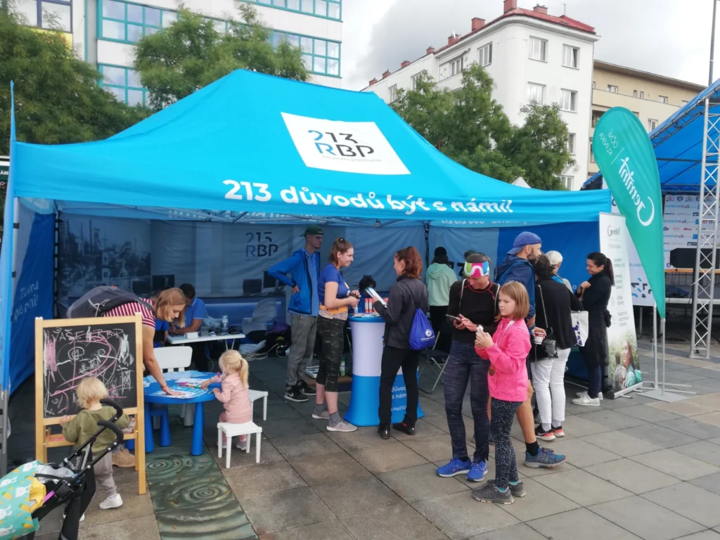 Blue RBP Health Insurance event tent at an outdoor public gathering, with adults and children taking part in family activities and information services.